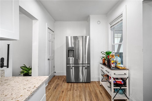 3026 Kingsland Ave, Bronx, NY 10469 - kitchen featuring light stone countertops, ornamental molding, white cabinets, stainless steel fridge with ice dispenser, and light hardwood / wood-style floors