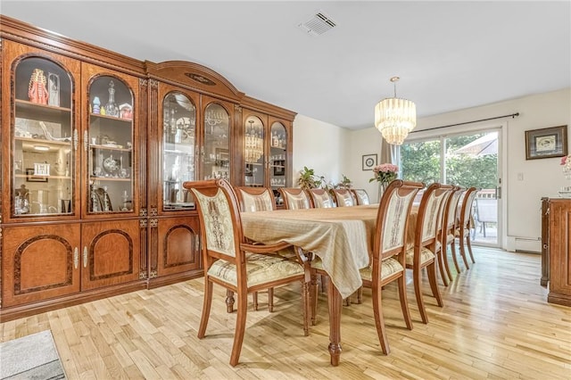 dining area featuring light wood-type flooring and an inviting chandelier