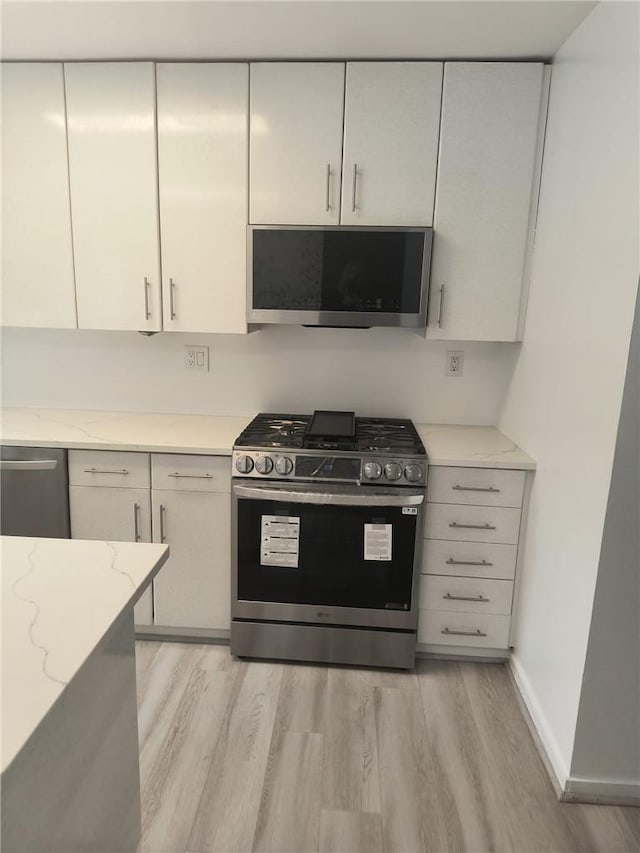 kitchen featuring light stone countertops, stainless steel appliances, and light hardwood / wood-style flooring