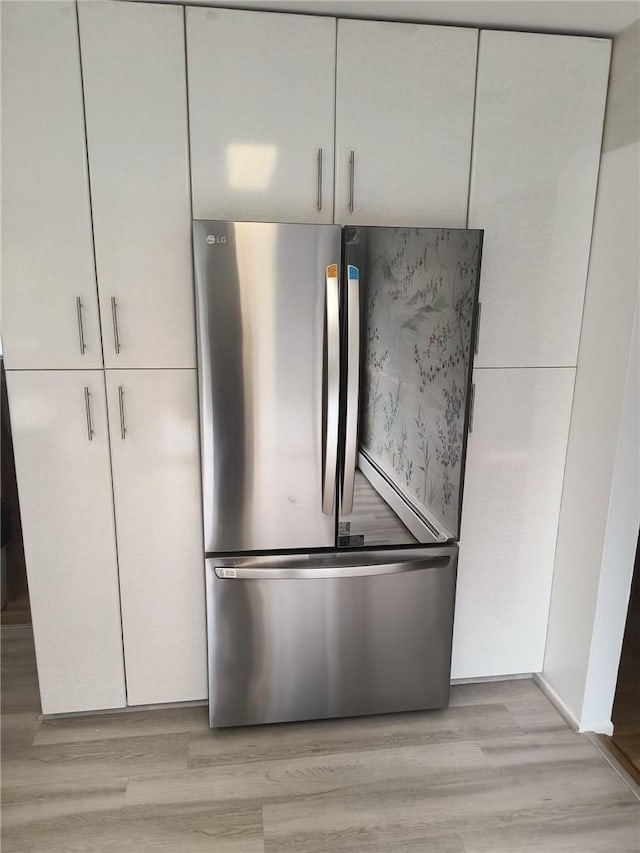 interior details featuring white cabinetry, stainless steel fridge, and light hardwood / wood-style floors