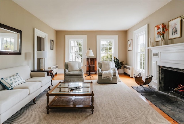 living room featuring a high end fireplace, radiator heating unit, and hardwood / wood-style flooring