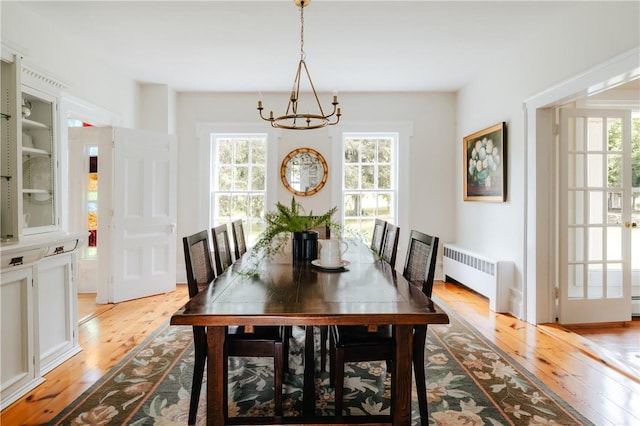 dining space with an inviting chandelier, light hardwood / wood-style flooring, and radiator