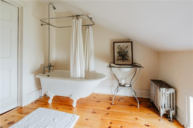 bathroom featuring shower / bath combo with shower curtain, wood-type flooring, and vaulted ceiling