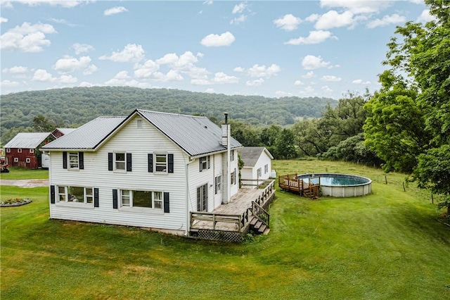 rear view of house with a lawn and a swimming pool side deck