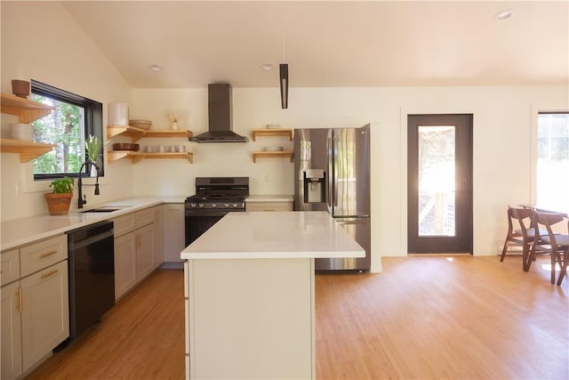 kitchen featuring light wood-type flooring, wall chimney exhaust hood, sink, black appliances, and a center island