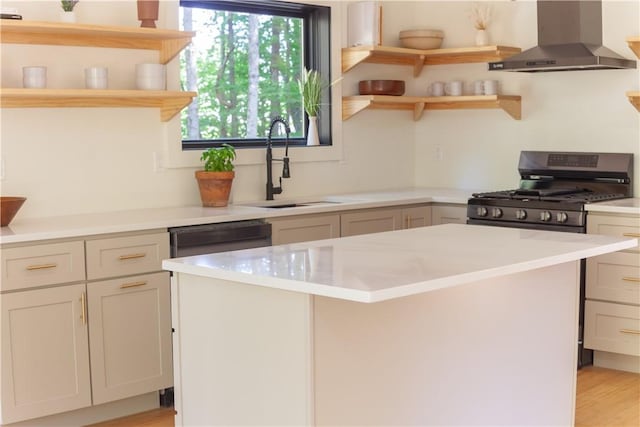 kitchen with black gas stove, sink, wall chimney exhaust hood, light wood-type flooring, and a kitchen island