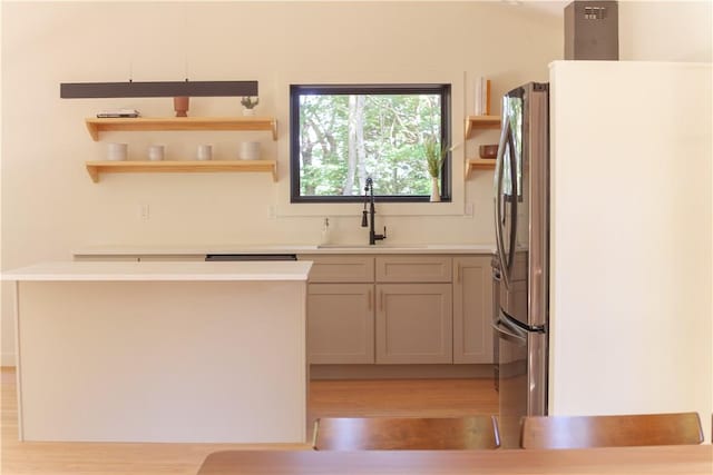 kitchen with light hardwood / wood-style floors, sink, and stainless steel refrigerator