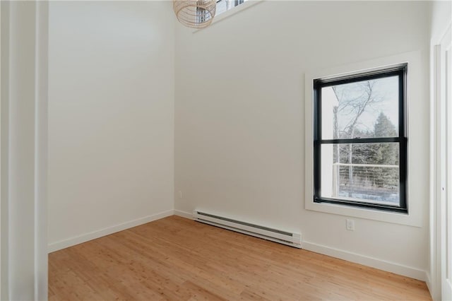 empty room with light hardwood / wood-style flooring, a baseboard heating unit, and a notable chandelier