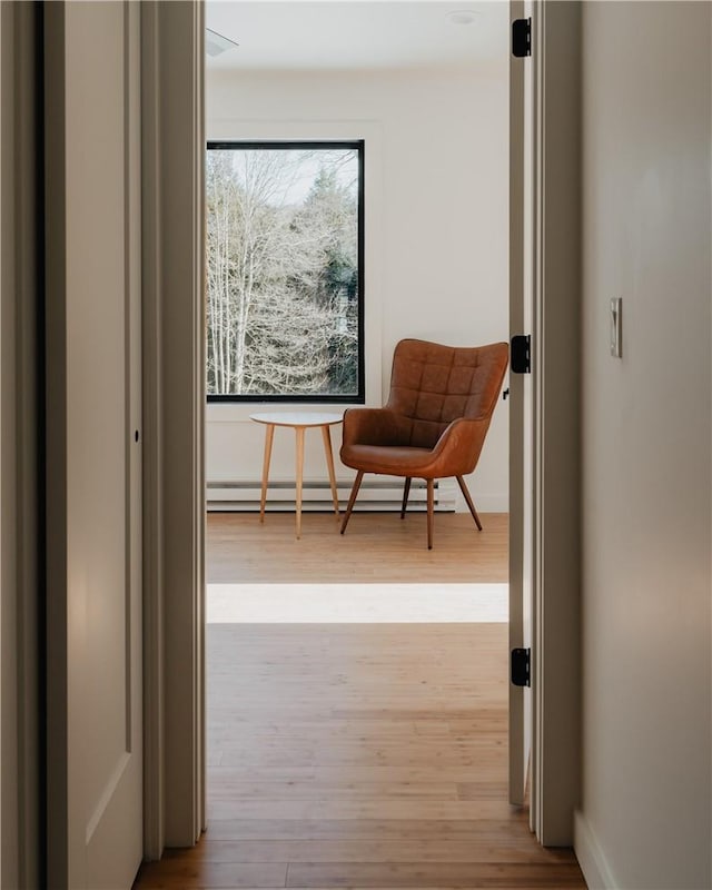 corridor with light hardwood / wood-style floors and a baseboard heating unit