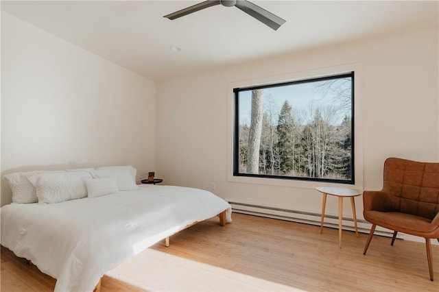 bedroom with baseboard heating, ceiling fan, and light hardwood / wood-style flooring