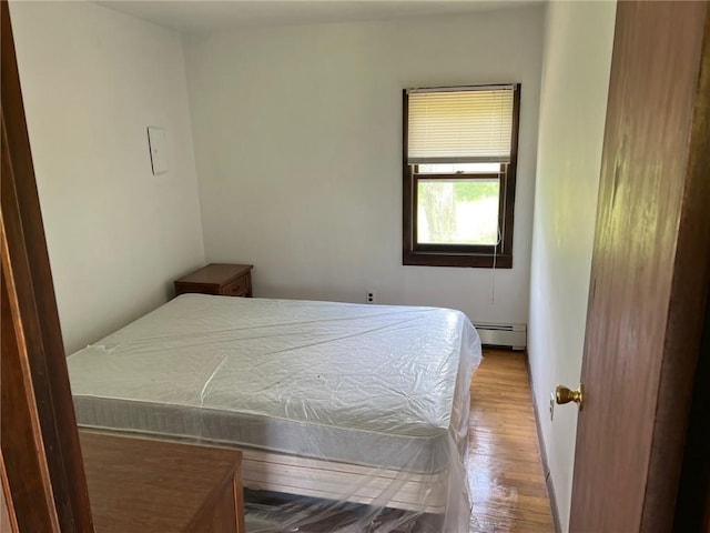 bedroom with hardwood / wood-style flooring and baseboard heating