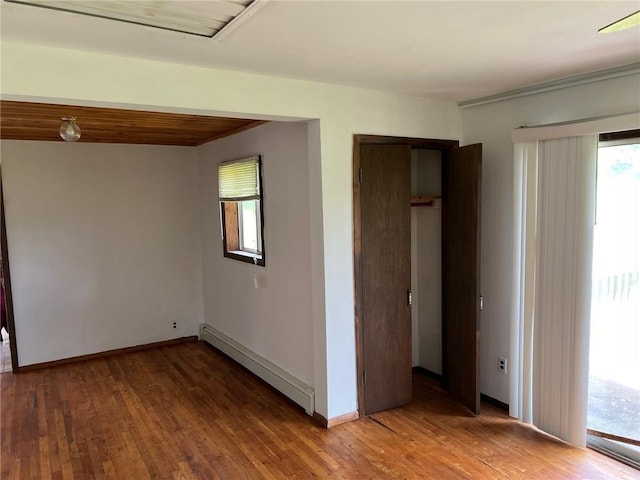 unfurnished room with baseboard heating and wood-type flooring