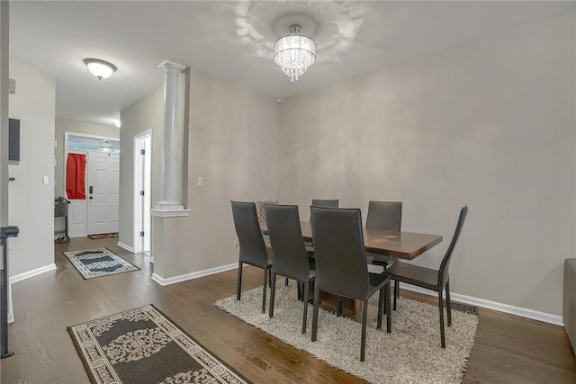 dining room with decorative columns, dark wood-type flooring, and a notable chandelier