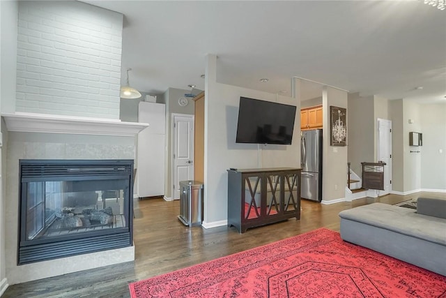 living room with a multi sided fireplace and dark hardwood / wood-style flooring