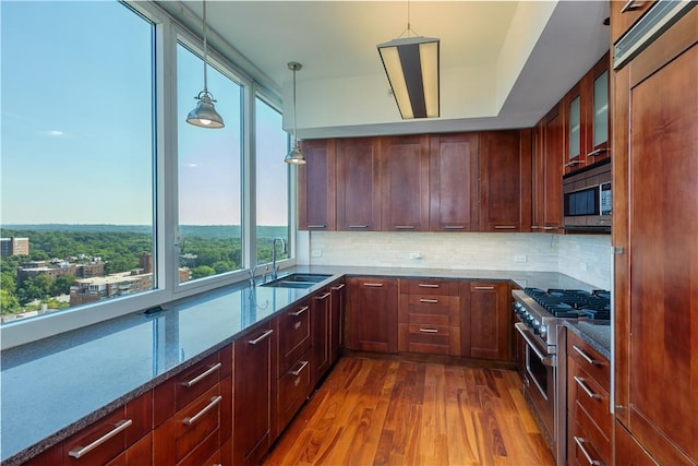 kitchen with dark stone counters, dark wood-type flooring, decorative light fixtures, and appliances with stainless steel finishes