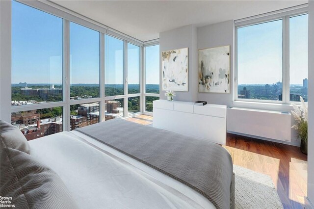 bedroom featuring hardwood / wood-style floors, radiator heating unit, and floor to ceiling windows