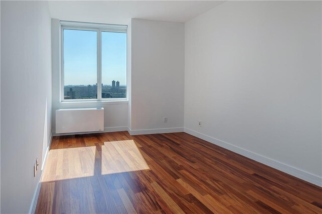 empty room with wood-type flooring and radiator