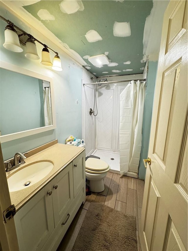 bathroom with a shower with curtain, vanity, wood-type flooring, and toilet