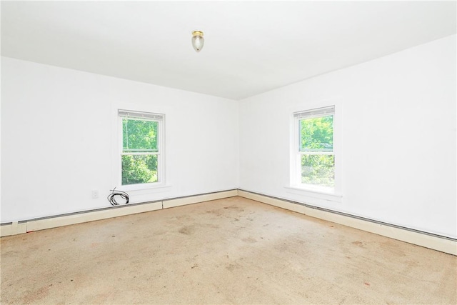 carpeted spare room featuring a healthy amount of sunlight and a baseboard heating unit