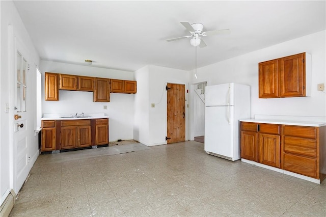 kitchen with ceiling fan, white fridge, sink, and baseboard heating