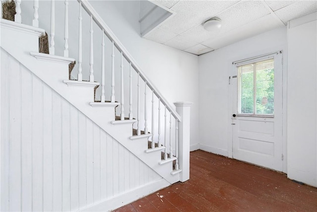 foyer featuring a paneled ceiling, wood walls, and dark wood-type flooring