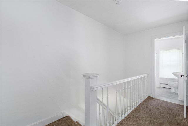 corridor with carpet floors and a baseboard heating unit