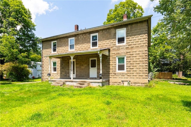 back of property with a lawn and a porch