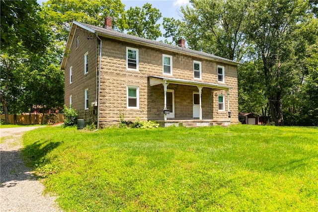 view of front of home featuring covered porch, central air condition unit, and a front yard