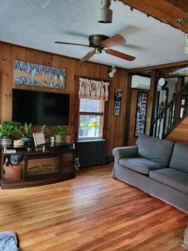 living room featuring wood-type flooring, radiator heating unit, and wooden walls