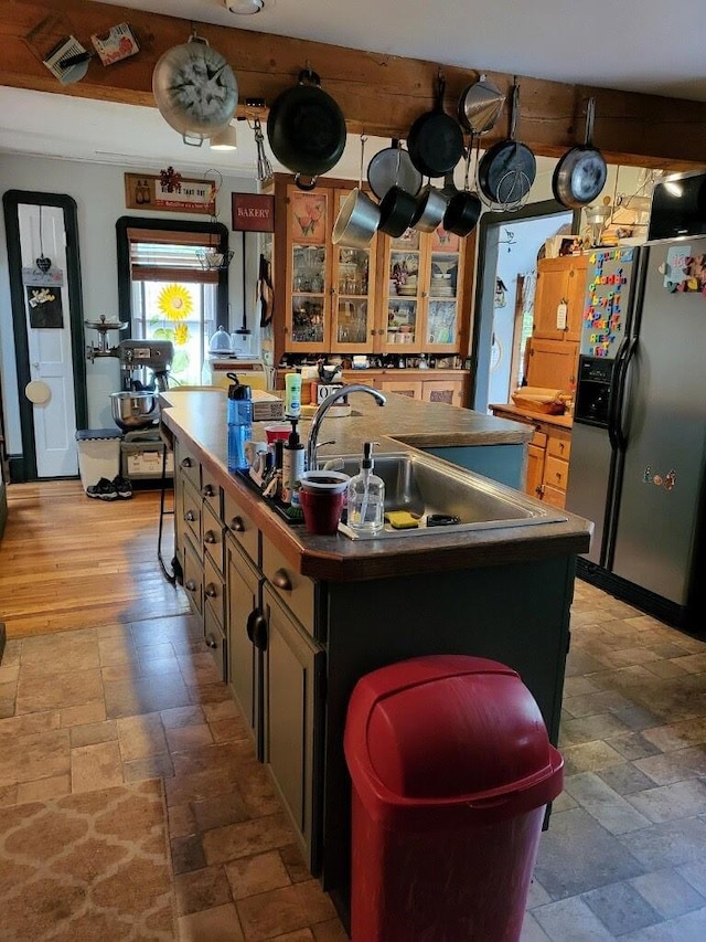 kitchen with stainless steel fridge, sink, and a kitchen island with sink