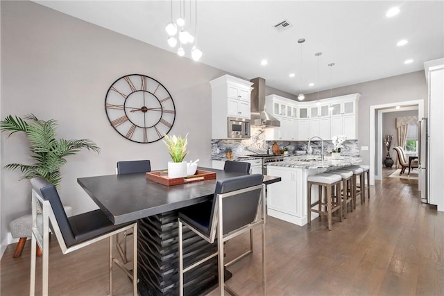 kitchen featuring pendant lighting, wall chimney exhaust hood, dark hardwood / wood-style flooring, and stainless steel appliances