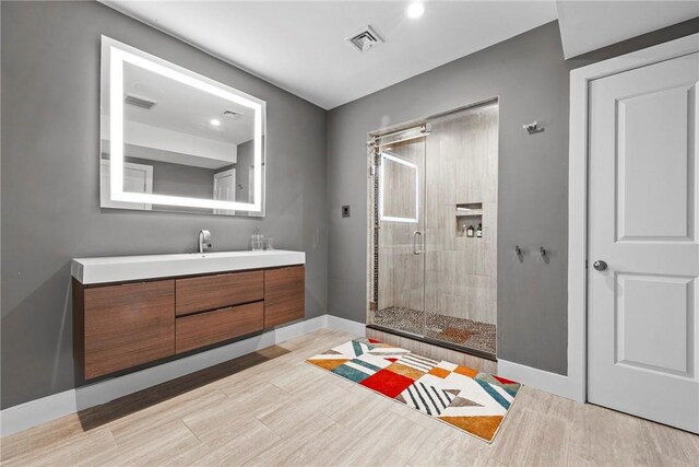 bathroom with hardwood / wood-style floors, vanity, and a shower with shower door