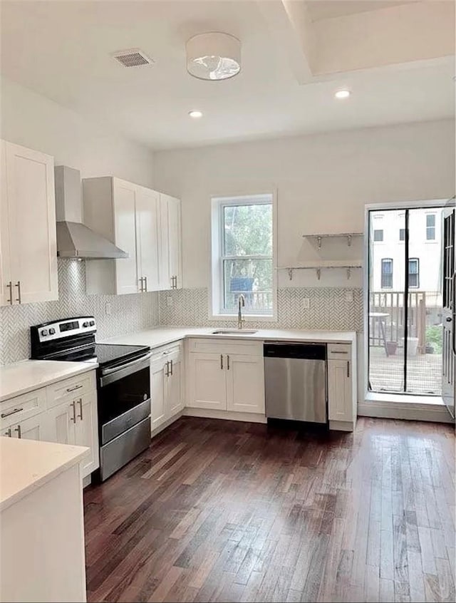 kitchen with dark hardwood / wood-style flooring, stainless steel appliances, white cabinetry, and wall chimney exhaust hood