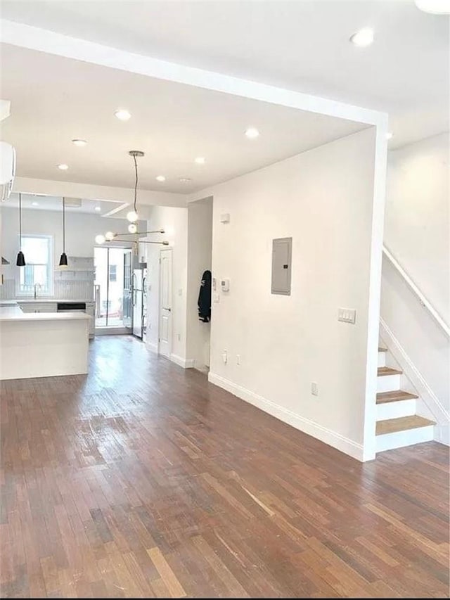 unfurnished living room featuring wood-type flooring, electric panel, ceiling fan, and sink