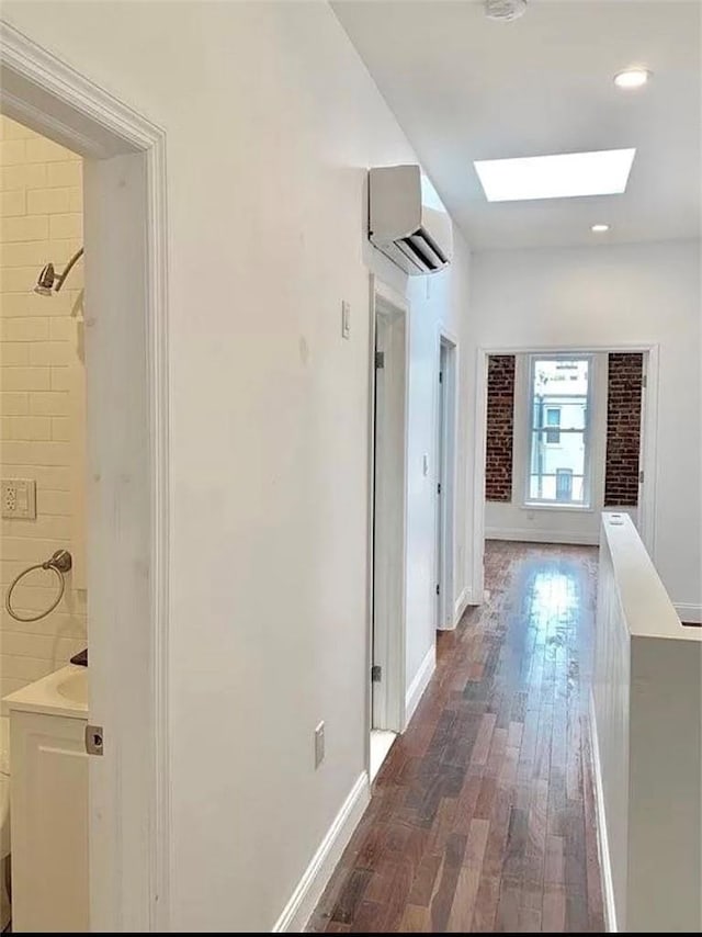 hall featuring an AC wall unit, dark wood-type flooring, and a skylight