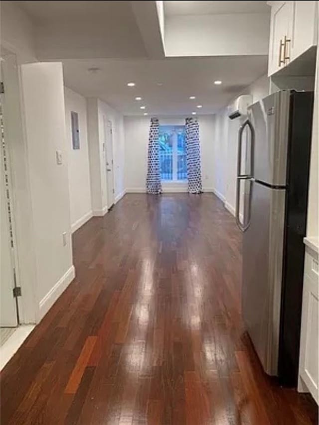 kitchen featuring white cabinetry, a wall mounted AC, stainless steel fridge, and dark hardwood / wood-style floors