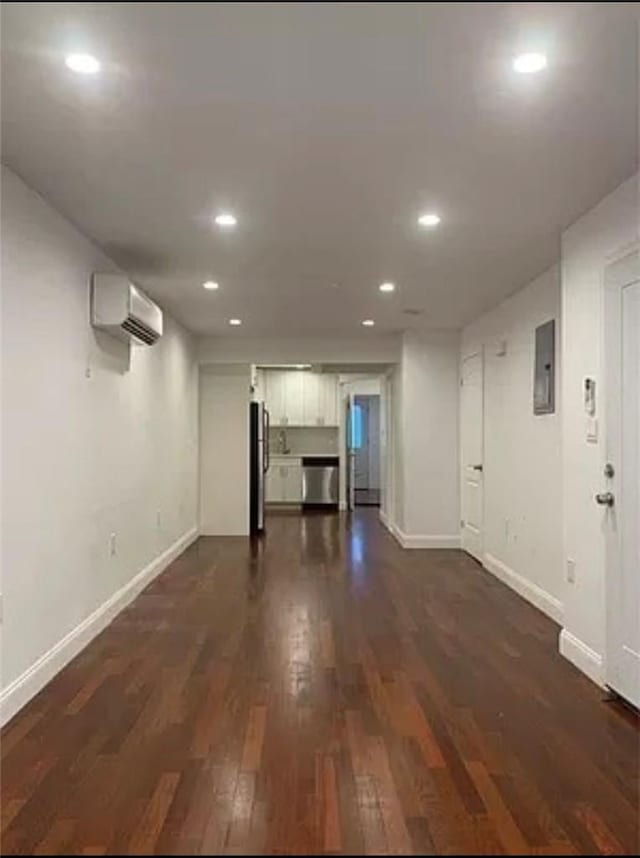 basement with electric panel, dark wood-type flooring, stainless steel refrigerator, and an AC wall unit