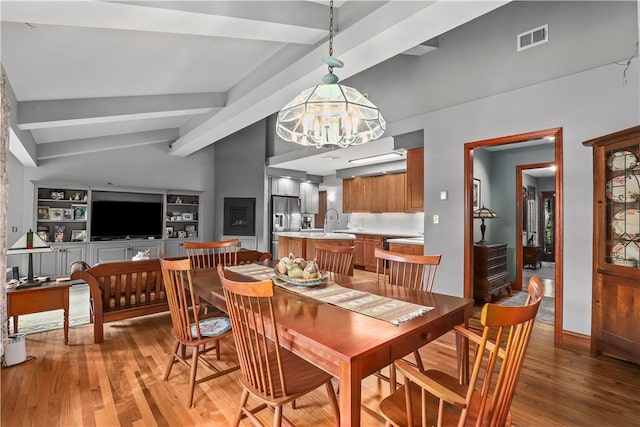 dining room featuring a chandelier, hardwood / wood-style floors, lofted ceiling with beams, and sink