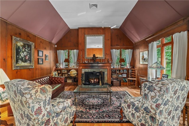 living room featuring wooden walls, light hardwood / wood-style flooring, and vaulted ceiling