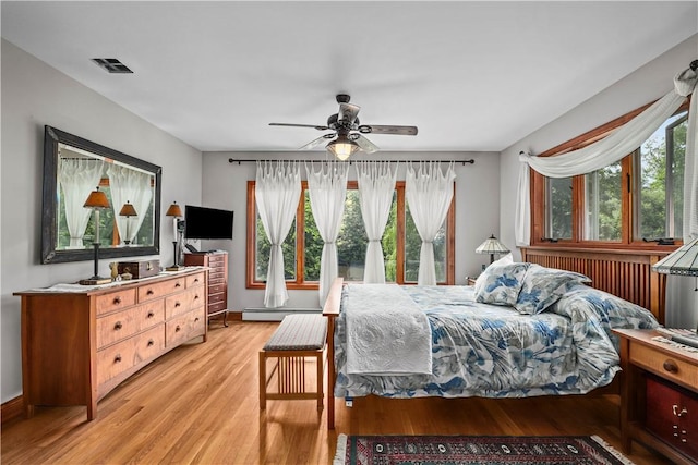 bedroom with a baseboard radiator, light hardwood / wood-style flooring, multiple windows, and ceiling fan