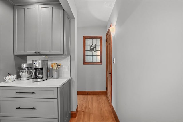 bar featuring gray cabinets, decorative backsplash, and light wood-type flooring