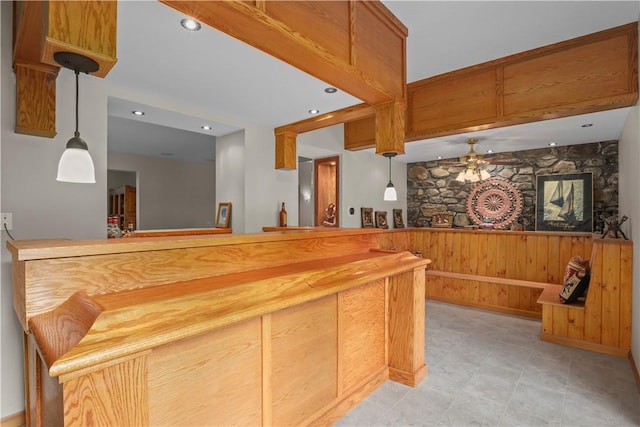 kitchen with ceiling fan, wooden walls, and hanging light fixtures