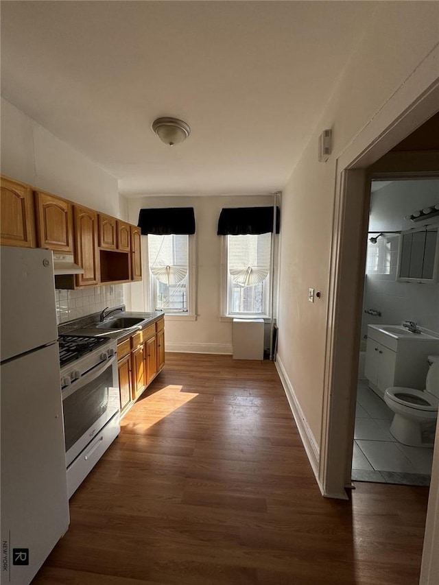 kitchen featuring dark hardwood / wood-style flooring, backsplash, sink, white fridge, and stainless steel range with gas stovetop