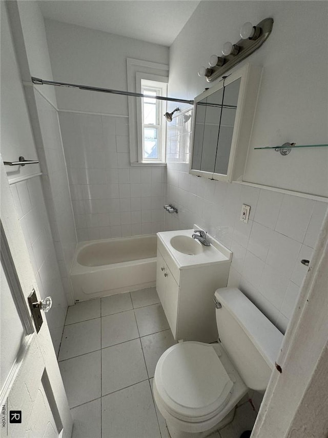 full bathroom with vanity, tiled shower / bath combo, tile walls, tile patterned flooring, and toilet