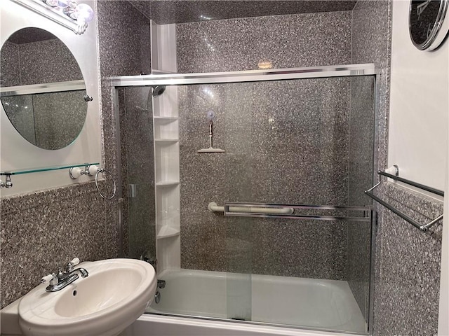 bathroom featuring sink, enclosed tub / shower combo, and tile walls