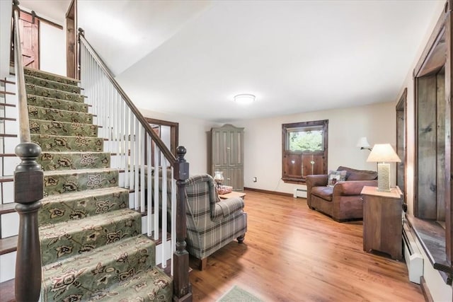 living room featuring vaulted ceiling, a baseboard radiator, and light hardwood / wood-style flooring