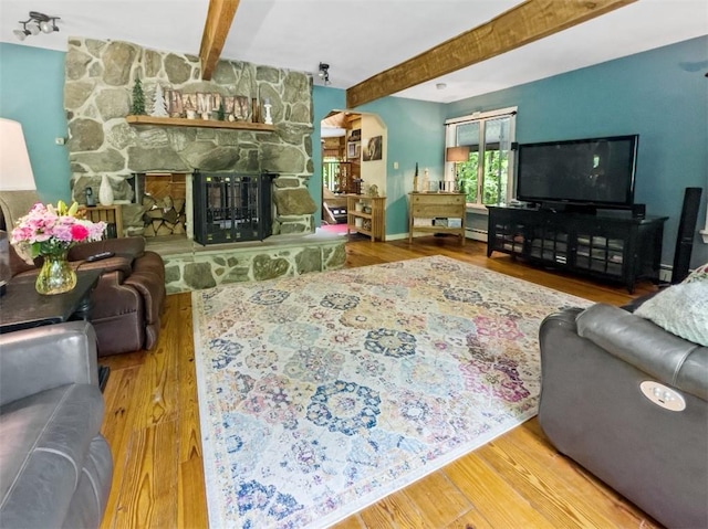 living room with a fireplace, wood-type flooring, and beam ceiling