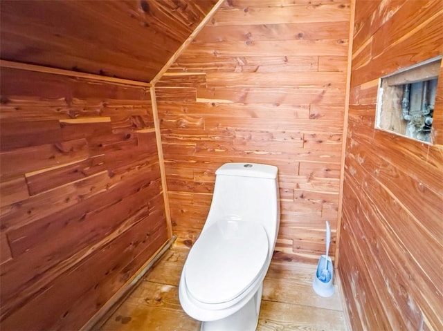 bathroom with toilet and wood walls