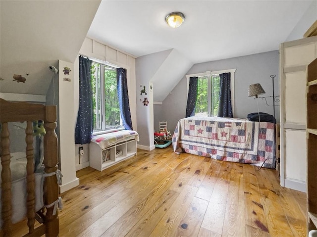 bedroom with light hardwood / wood-style floors and lofted ceiling