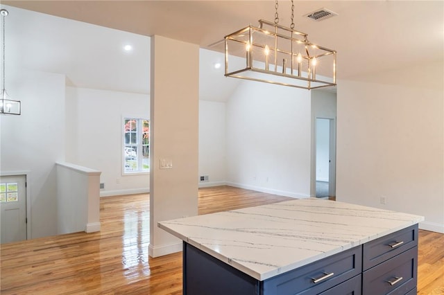 kitchen featuring light stone counters, pendant lighting, a center island, and light hardwood / wood-style floors